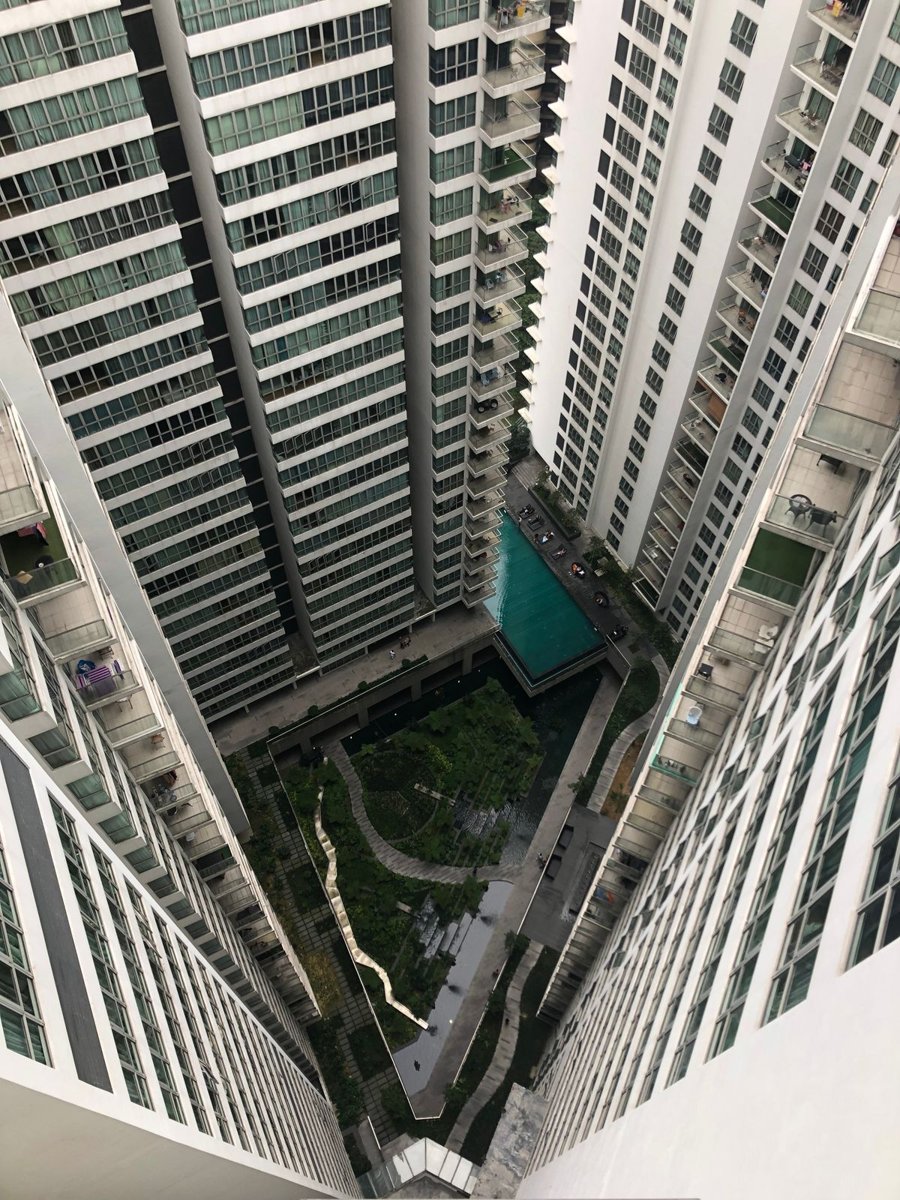 Looking down between tall residential towers into a landscaped courtyard with a pool